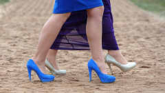 Kuva kahden korkokengissä kävelevän naisen jaloista. 