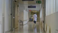 Kuva sairaalan käytävästä, jota pitkin kävelee lääkäri