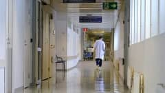Kuva sairaalan käytävästä, jota pitkin kävelee lääkäri