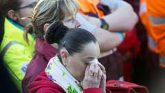 Nainen pyyhkii kyyneleitä nenäliinalla Brysselin lentokentällä järjestetyssä muistotilaisuudessa. 