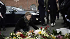 Nainen laskee kukkia uhrien muistoksi.