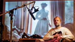 Heikki Kossi studiollaan, taustalla Nicole Kidman valkokankaalla elokuvassa Lumotut.
