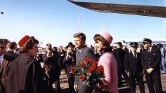 John F. Kennedy ja Jacqueline Kennedy lentokentällä. Heidän ympärillään on ihmisiä.
