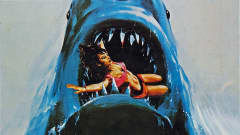 Hain avonainen kita. Veristen hampaiden välissä kamppailee uima-asuinen nainen. 