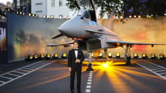 Tom Cruise poseeraa hävittäjäkoneen edessä.