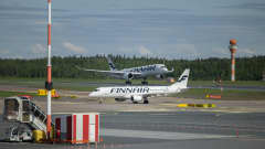 Kaksi Finnairin sinivalkoista konetta Helsinki-Vantaan lentokentällä, etualalla lentokenttäkalustoa.