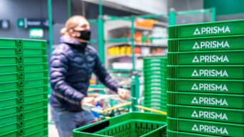 Henkilö ostoskärryn kanssa ostoskorien vieressä Prismassa.