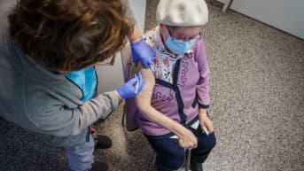 Sairaanhoitaja pistää koronarokotteen vanhuksen käsivarteen.