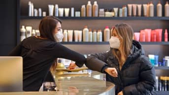 WHO:nKaksi naista tekee kyynärpäätervehdyksen kampaamossa.