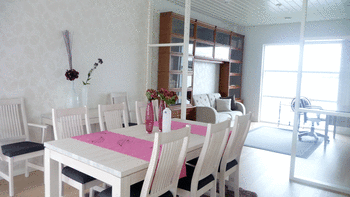 Kuvassa ruokapöytä ja tuoleja, pöydällä kaksi pöytäliinaa ja maljakoita