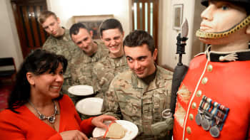 Nainen tarjoilee sotilaille kakkua.