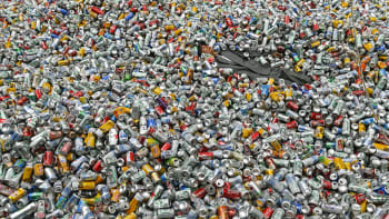 Taiteilija makaa kymmenien tuhansien tyhjien metallisten juomatölkkien seassa.