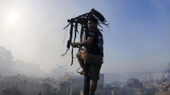 Mies kiipeää sähköpylvääseen ja katseleen tulipalossa tuhoutunutta asuinaluetta.