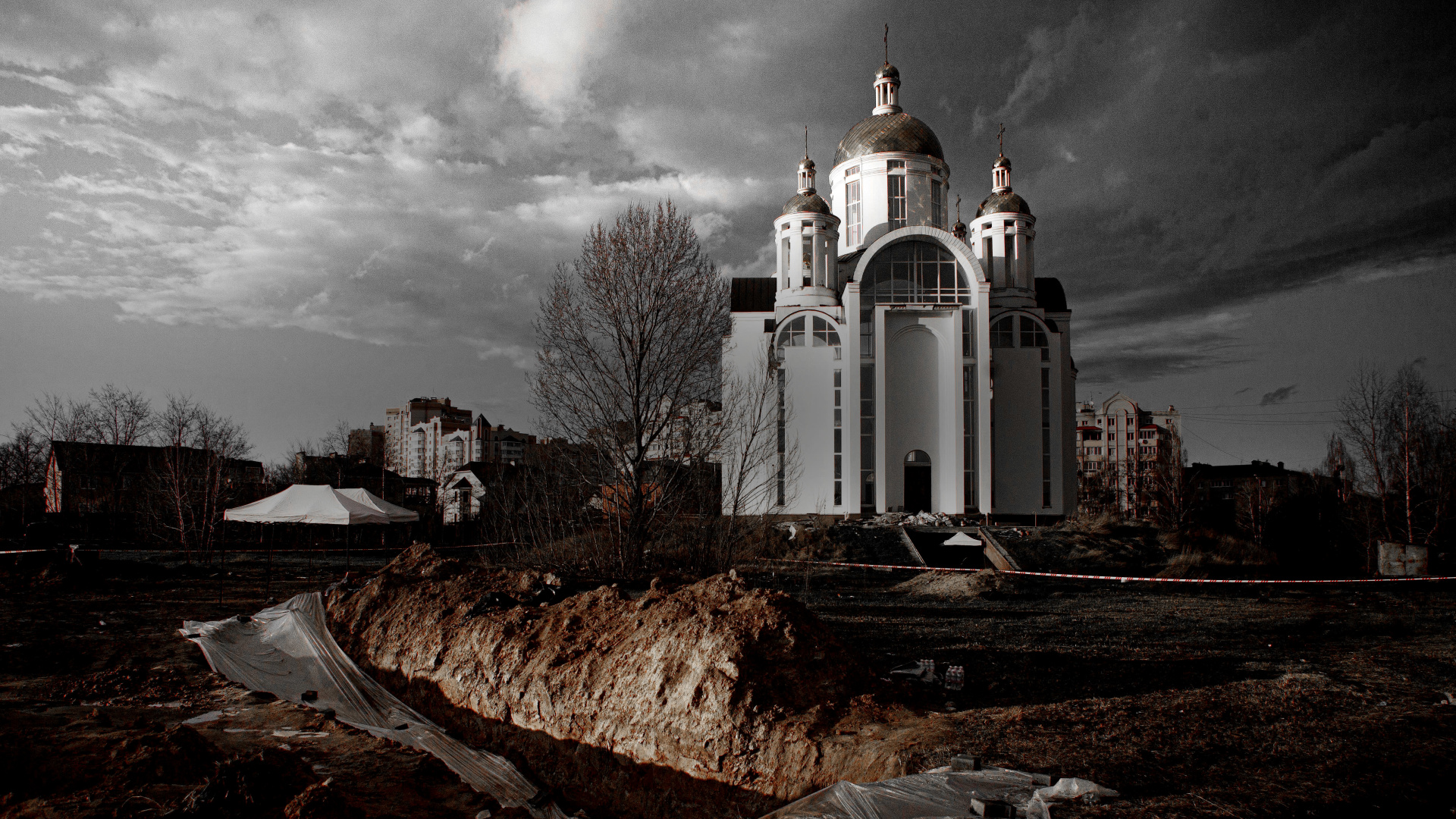Ukrainassa Butšan hautausmaa ja kirkko, etualalla joukkohauta kaivettuna. 