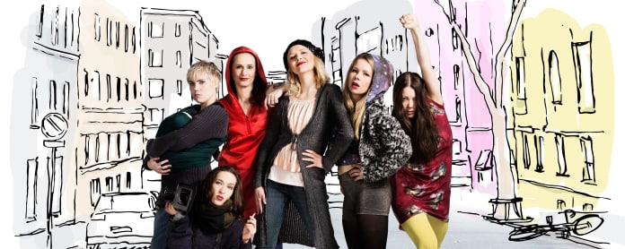 Mä halusin olla Suffragetti -musikaalikomedian naisten ryhmäkuva. Taustalla piirretty kaupunkigrafiikka.