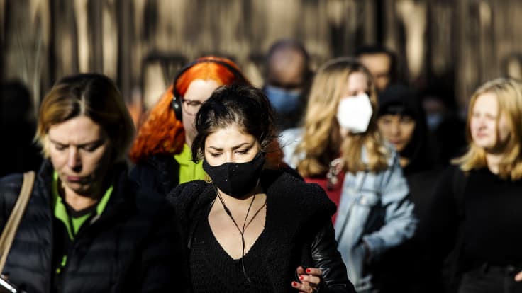 Maski kasvoillaan kulkevia ihmisiä Helsingin keskustassa.