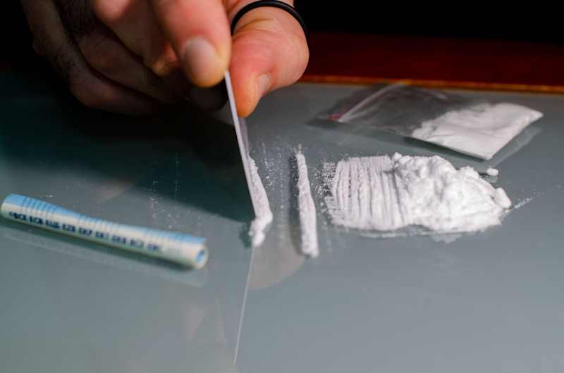 Cocaine lines on the table.  The picture shows a hand that breaks down the substance.