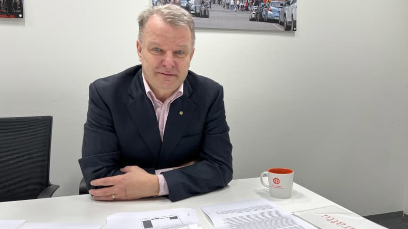 Директор з продажу OP Koti Päijät-Häme Хейккі Райтанен сидить за столом, поклавши руки на стіл, дивиться на камеру.  Кавовий гурток OP і документи на столі.