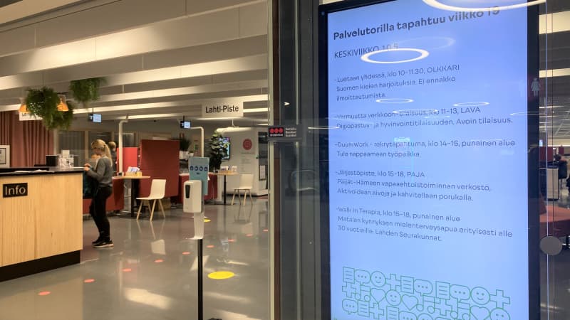 Lähikuvass is a digital display board in Lahti Palvelutori.  In the background is a service counter with a person.