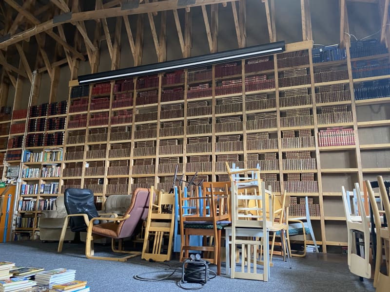 There are chairs on the stage of the storage hall and the wall is full of books.
