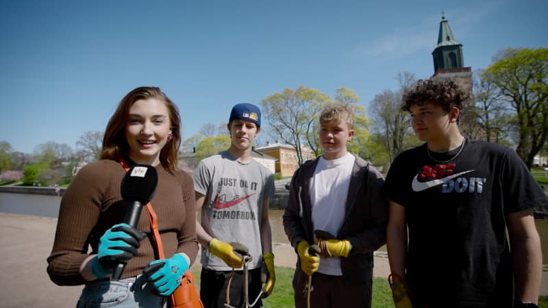 A female reporter interviews three young boys on the bank of Aurajoki.