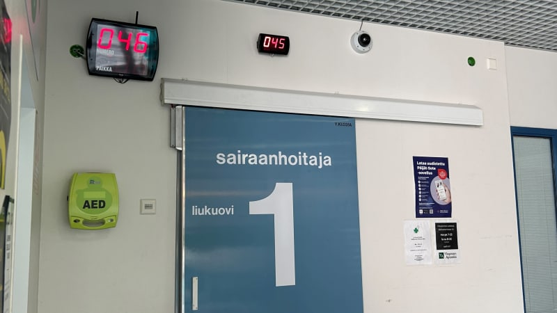 Крупным планом — синяя дверь с надписью «медсестра».  На стене имеется цифровое табло с номером смены.