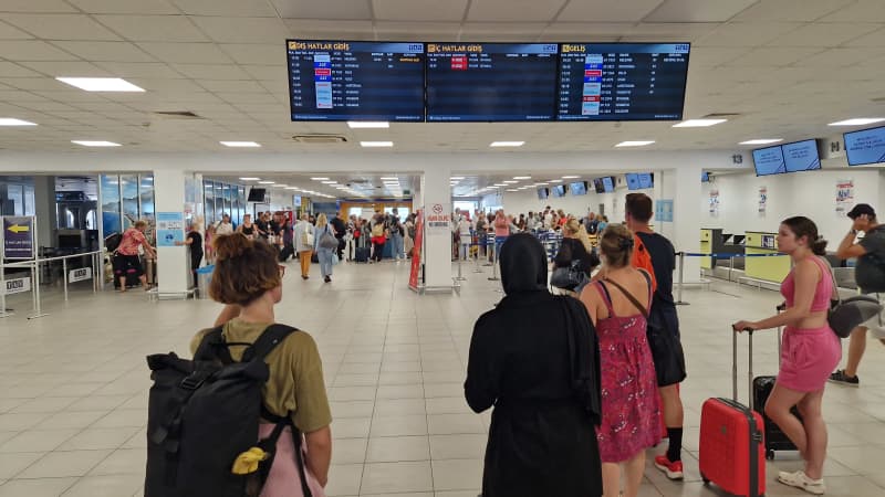 Passengers in the terminal of Gazipasa Airport in Alanya looking at the display board of departing flights