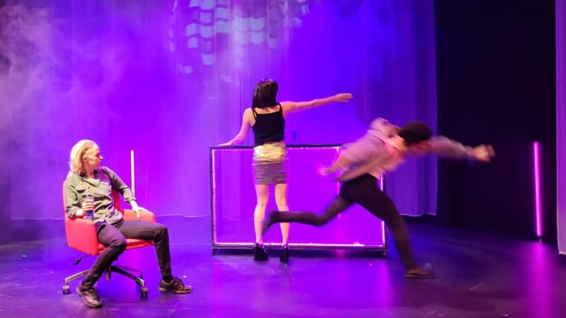 Three female actors performing on a theater stage