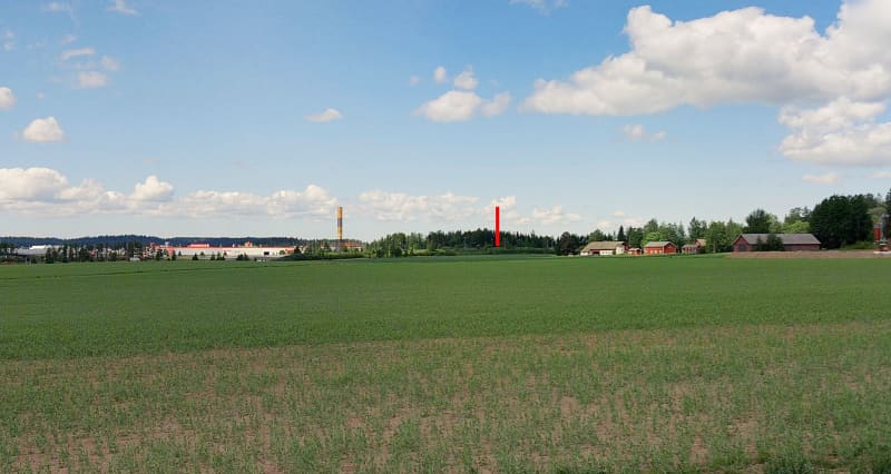 The landscape that opens up from the field on the horizon, showing commercial buildings and farm buildings.  In the middle of them is a yellow advertising post and a vertical bar drawn in red.  There are clouds in the blue sky.