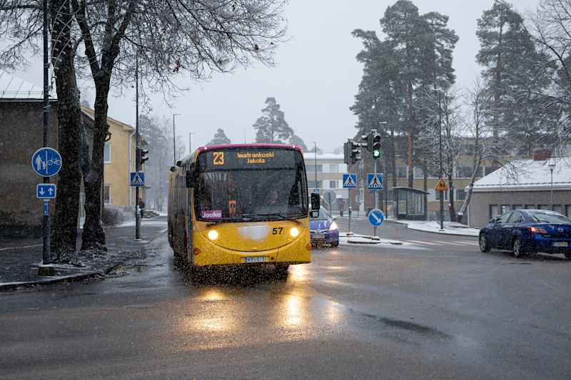 Bus number 23 in the snowfall through the intersection in an urban area.