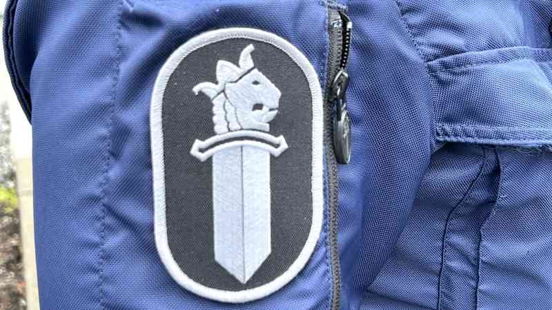 Close-up is the blue sleeve of the police officer with a sleeve mark and a police logo, or a sword and lion pictures on a black background.