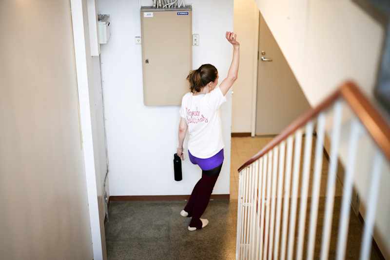 The person raises his hands in the staircase.