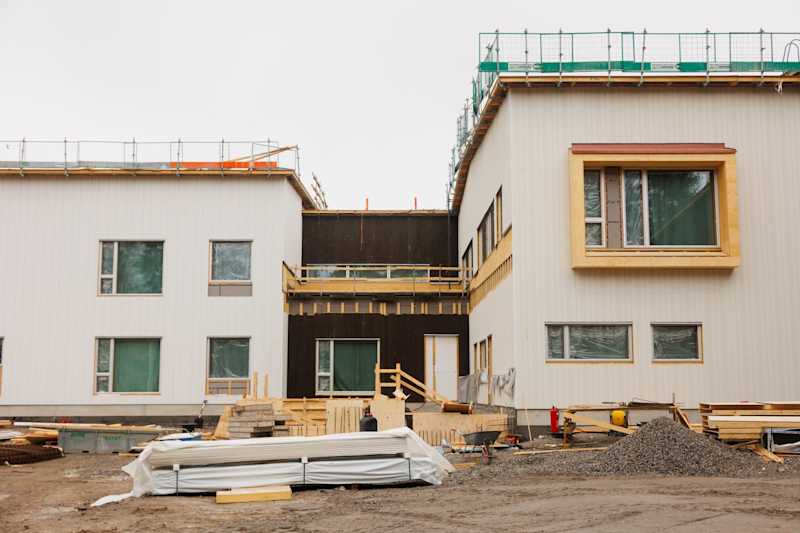Close -up is the facade of a light school building under construction.  There is building material in the country.
