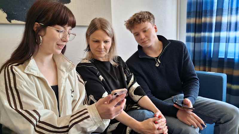 Seinäjoki High School seniors Lilja Panula and Pete Antila and teacher Hanna Olli look at pictures of the group's student exchange trip to France.