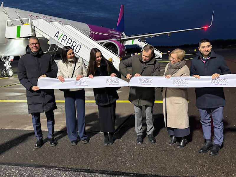 Lithuania's ambassador to Finland, Edvilkas Raudonikis, cuts the ribbon in front of a Wizz Air plane at Turku airport.