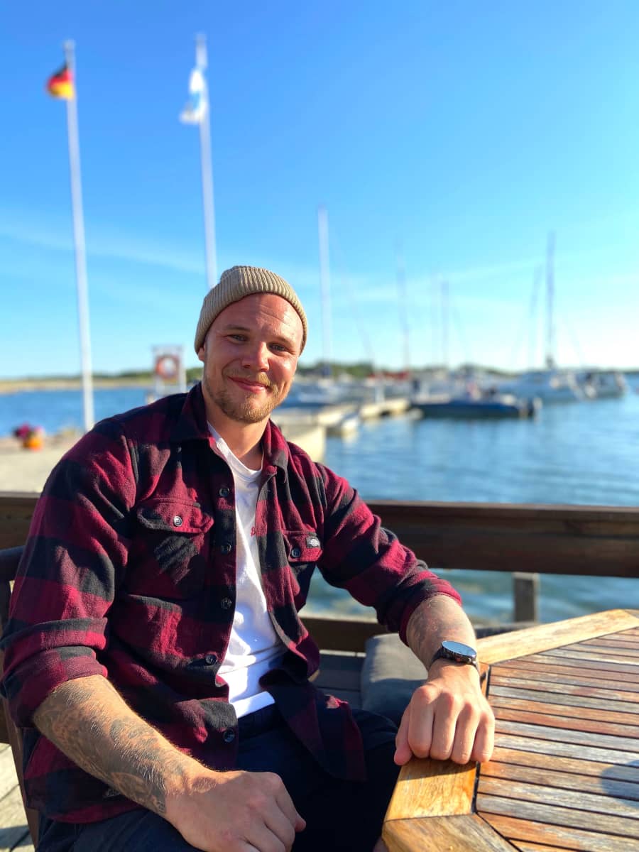 Jääkiekkoilija Taavi Vartiainen istuu ulkona pöydän ääressä satamassa.