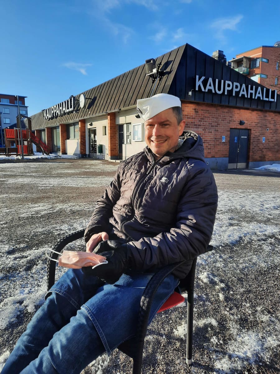 Kahvikioskiyrittäjä ja näyttelijä Jarno Kolehmainen istuu tuolissa kioskin ulkopuolella