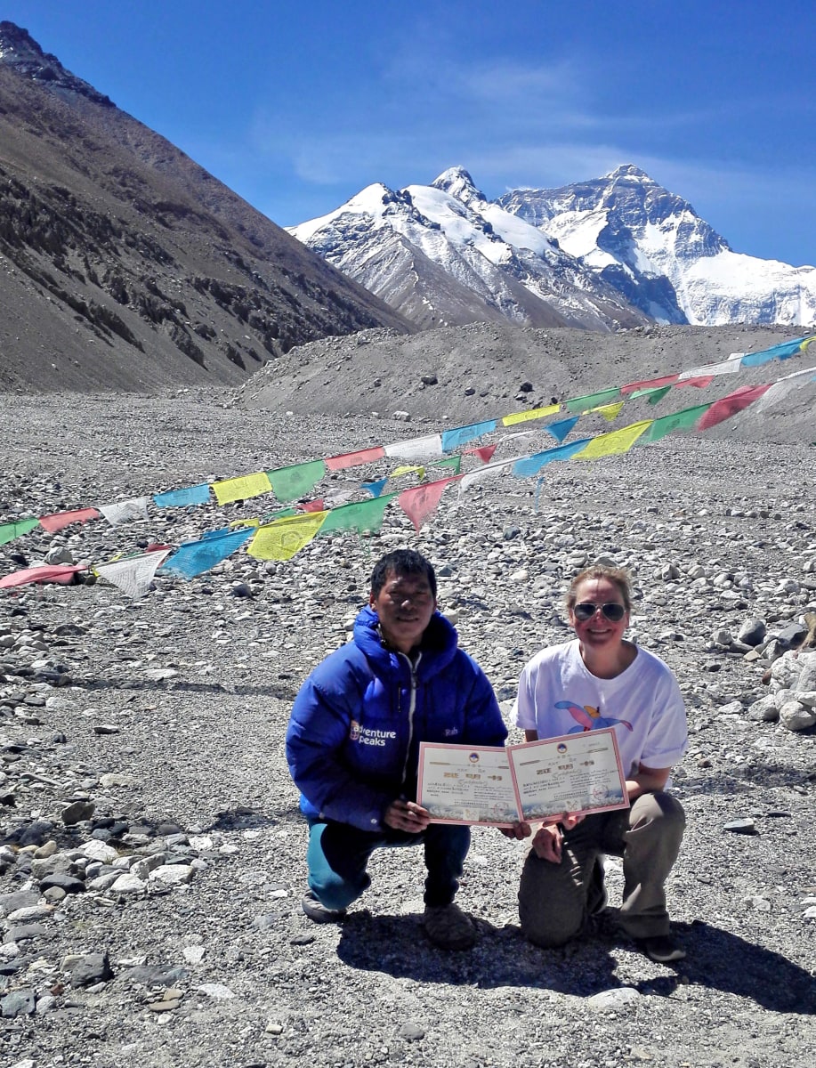 Paula Strengell (oikealla) vieressään sherpa Pemba. Molemmilla on todistukset kädessä. Taustalla näkyy Mount Everestin huippu.
