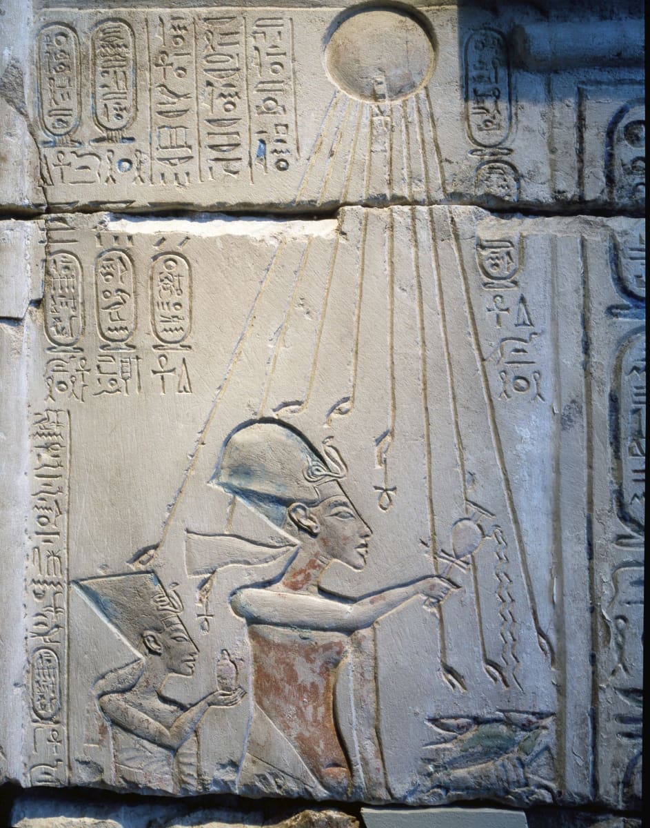 Aten-jumala kuvattiin auringonkiekkona, josta lähti käsipäisiä säteitä. Reliefissä faarao Akhenaten ja kuningatar Nefertiti uhraavat Atenille. Reliefi on aiempi löytö Amarnasta, jonne Akhenaten siirsi pääkaupungin. 