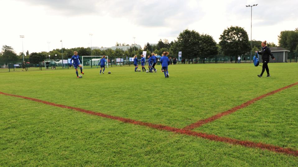 HJK:s juniorlag för flickor födda år 2007 värmer upp på en gräsplan i blåa träningskläder inför en match av Helsinki Cup 2019