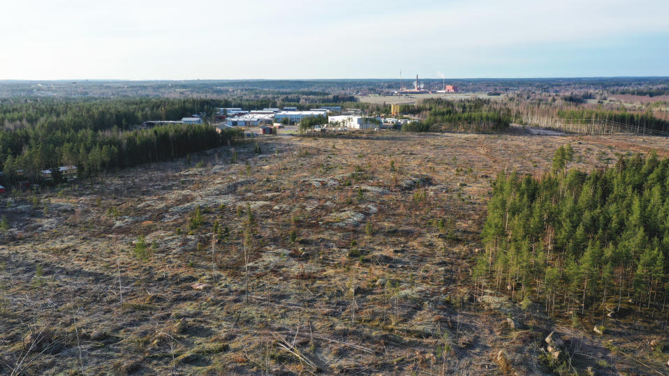 avohakattu metsä ylhäältä nähtynä, taustalla näkyy teollisuusalueen rakennuksia.