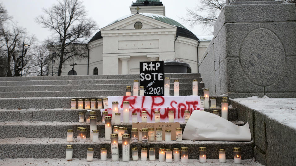 Kynttilämielenosoitus rokotuspakkoa vastaan Hämeenlinnan Kirkkopuiston portailla, taustalla Hämeenlinnan valkoinen kirkko.