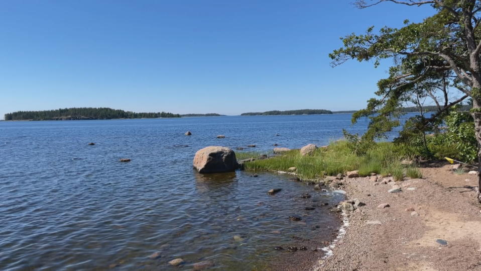 Merellinen maisema rantoineen, sininen taivas, aurinko paistaa.