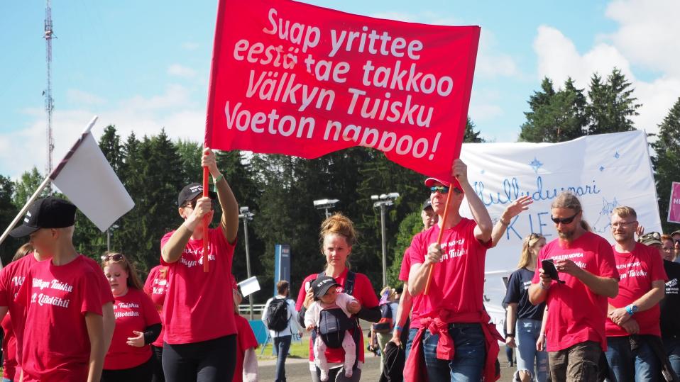 Välkyn Tuiskun kannattajia kulkemassa kulkueessa. Kaksi heistä pitelee suurta banderollia.