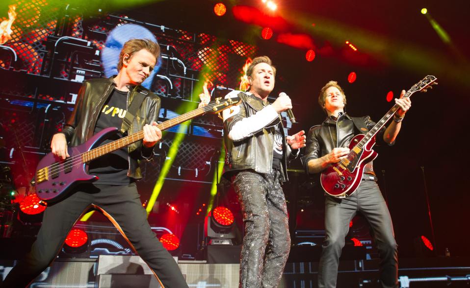 Duran Duranin John Taylor, Roger Taylor ja Simon Le Bon lavalla kitaroineen ja värivaloineen.