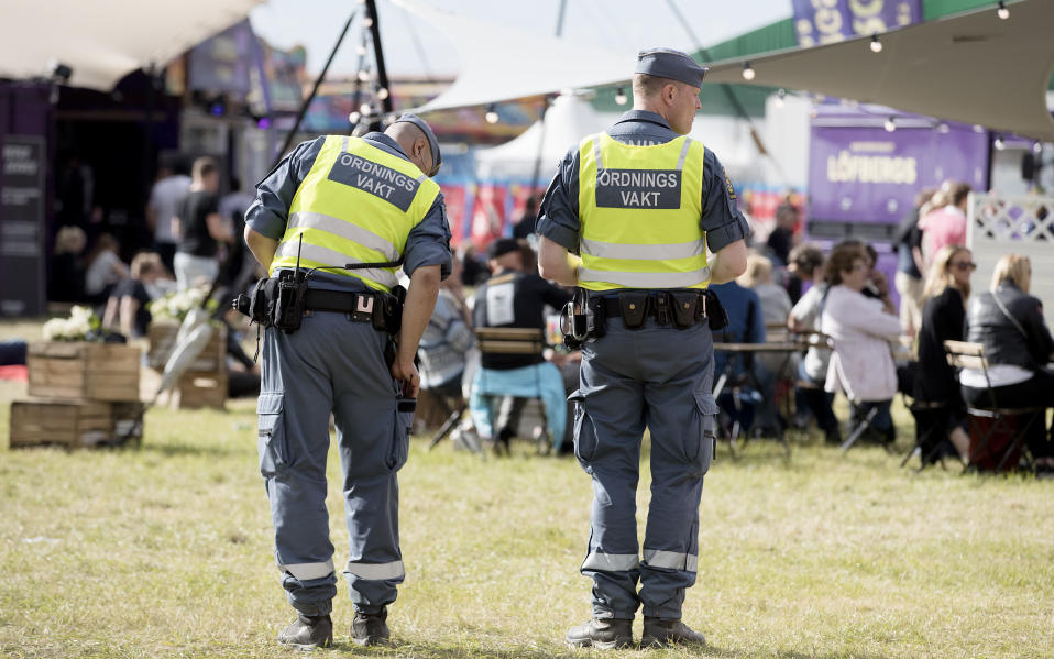 Kaksi järjestyksenvalvojaa katsoo ihmisjoukkoa festivaalialueella.