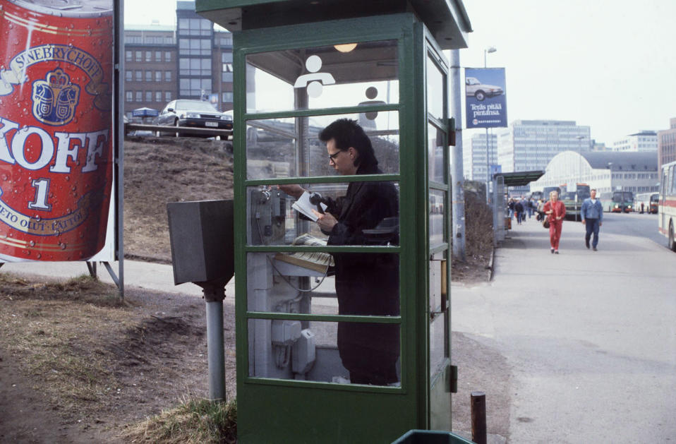 Nuori mies soittamassa puhelinkioskissa vuonna 1990.