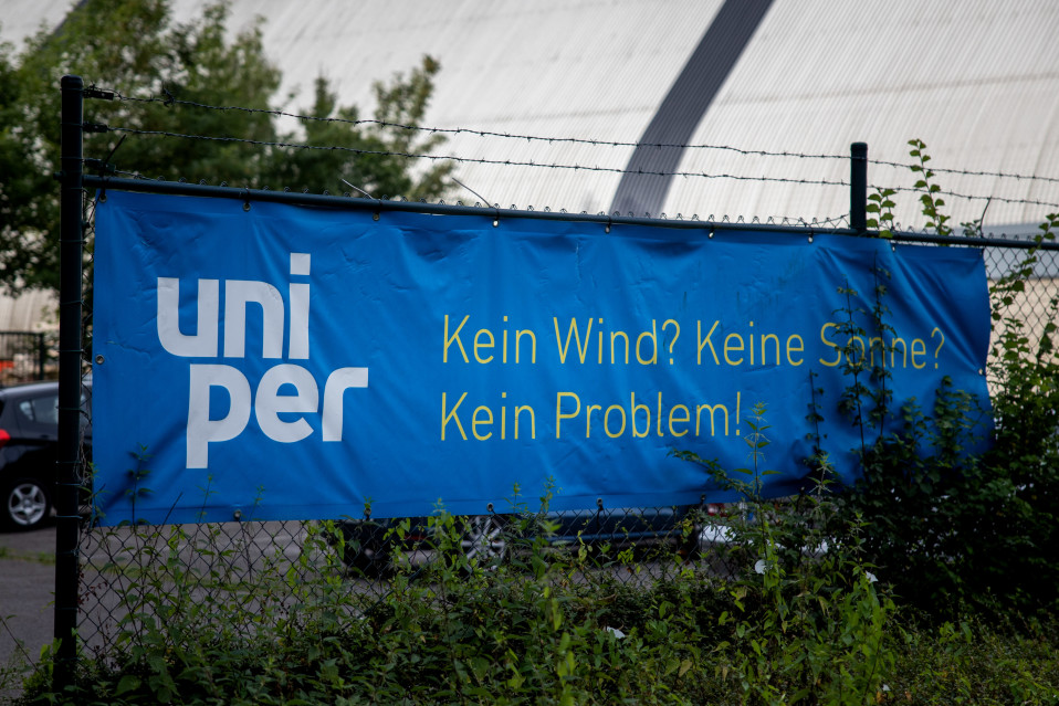 Piikkilanka-aidassa roikuvassa lakanassa on Uniperin värit sininen ja valkoinen.  Keltaisella lukee: Kein Wind? Kein Sonne? Kein Problem!