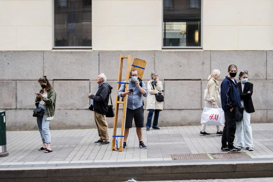 Aleksanterinkadun raitiovaunupysäkillä odottaneet käyttivät kasvomaskeja.