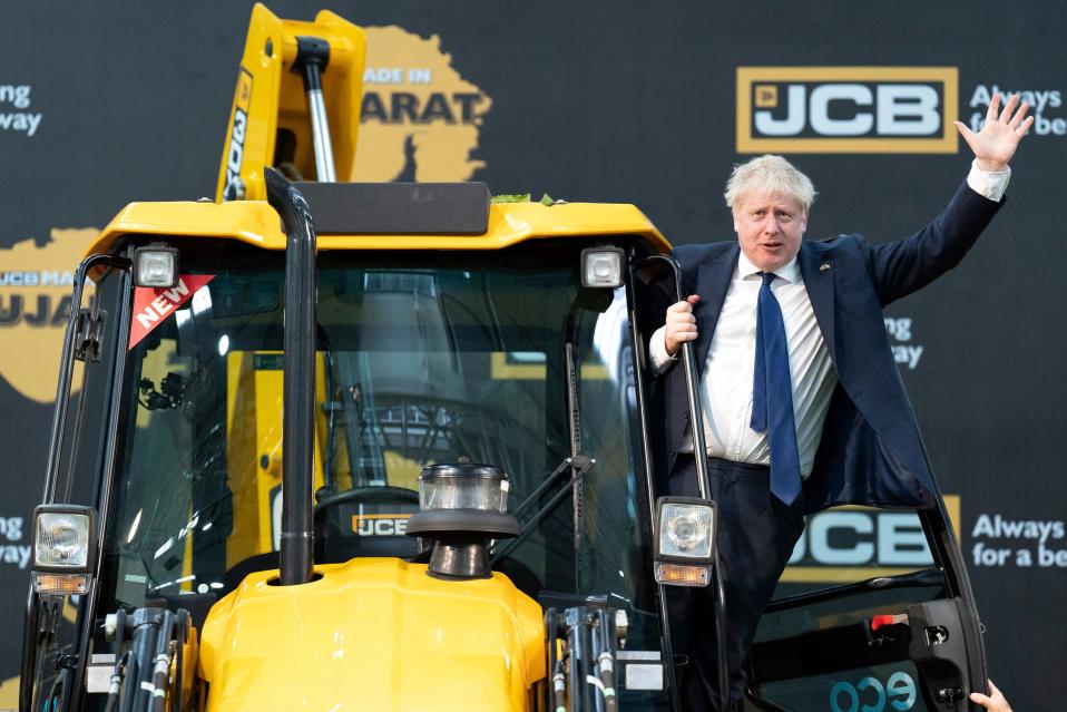 Boris Johnson tervehtii kaivinkoneesta.